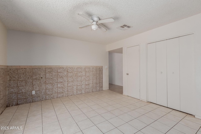 5933 W Mitchell Dr, Phoenix, AZ 85033 - unfurnished bedroom with wainscoting, a closet, a textured ceiling, and a ceiling fan