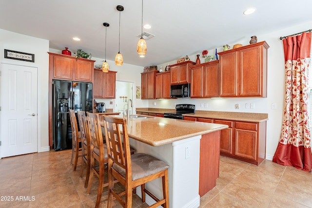 kitchen featuring pendant lighting, sink, a kitchen breakfast bar, black appliances, and a center island with sink