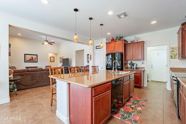 kitchen featuring sink, an island with sink, a breakfast bar area, and black appliances