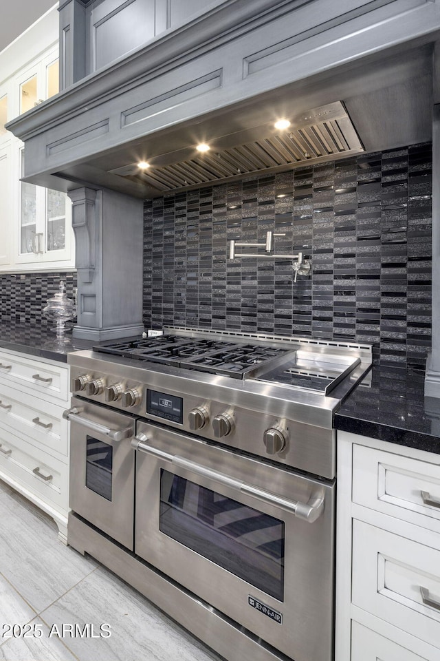 kitchen featuring range with two ovens, white cabinets, and decorative backsplash