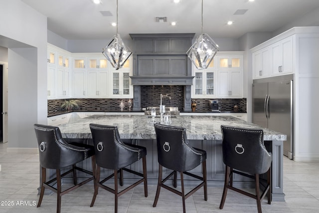 kitchen with built in fridge, white cabinetry, a breakfast bar area, and a spacious island