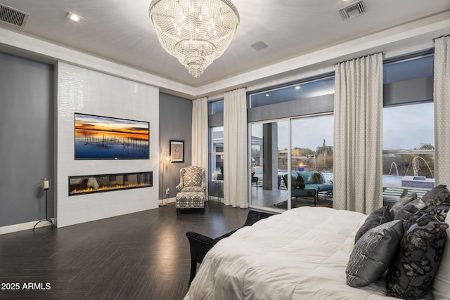 bedroom featuring an inviting chandelier, dark parquet flooring, a fireplace, and access to outside