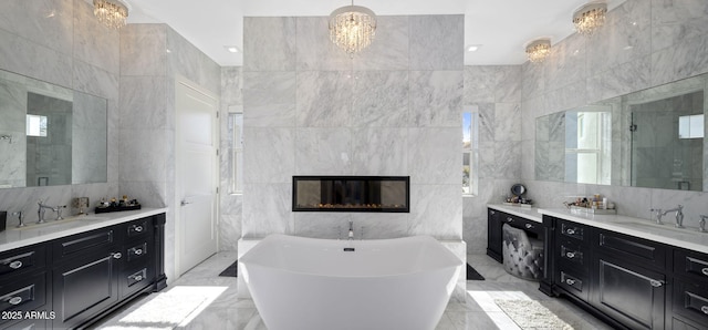 bathroom featuring tile walls, a tile fireplace, a chandelier, and separate shower and tub