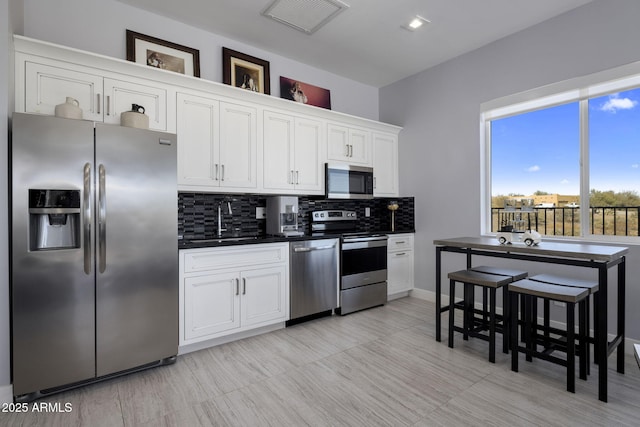 kitchen featuring appliances with stainless steel finishes, sink, decorative backsplash, and white cabinets