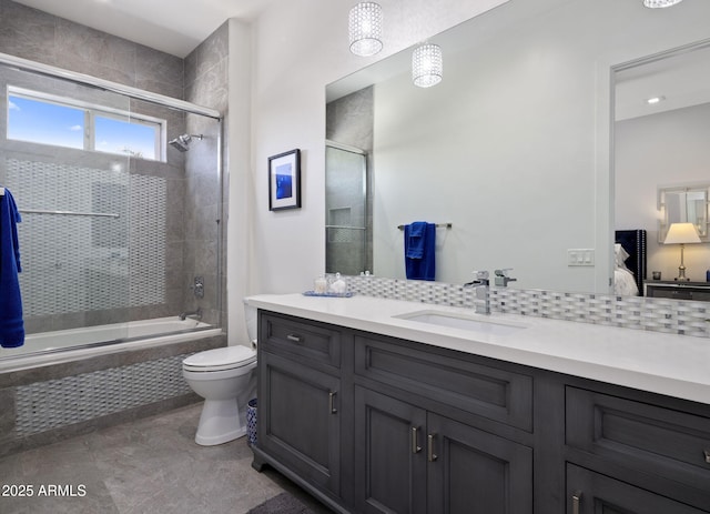 full bathroom with enclosed tub / shower combo, vanity, and toilet