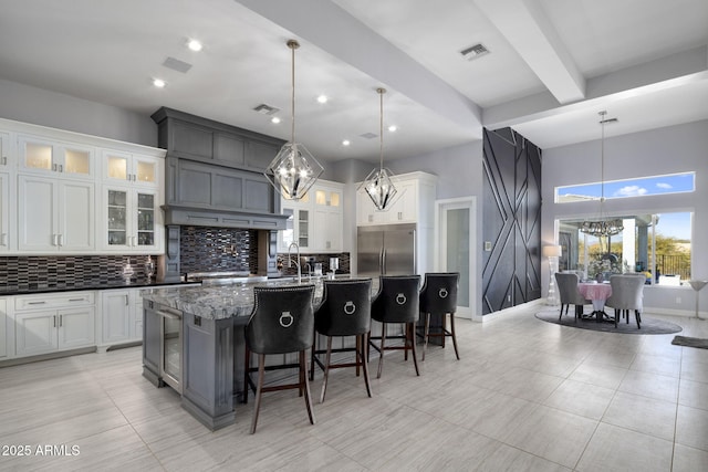 kitchen with white cabinets, a center island with sink, pendant lighting, and a notable chandelier