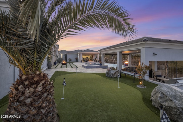 yard at dusk featuring a hot tub and a patio