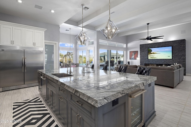 kitchen featuring sink, wine cooler, an island with sink, white cabinets, and stainless steel built in fridge