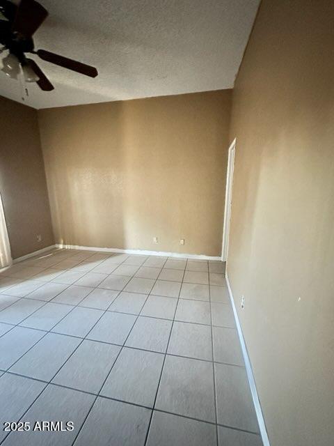 unfurnished room with a textured ceiling, ceiling fan, and light tile patterned flooring