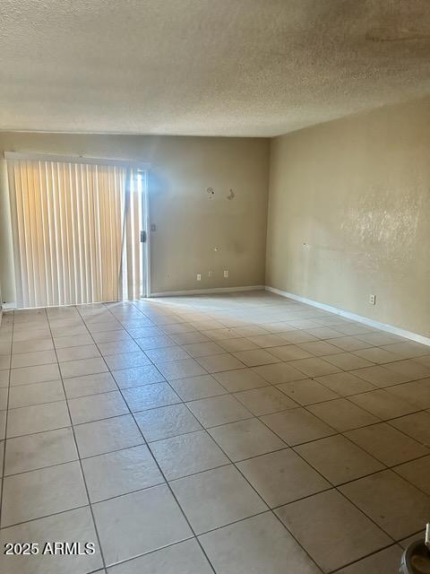 tiled empty room with a textured ceiling