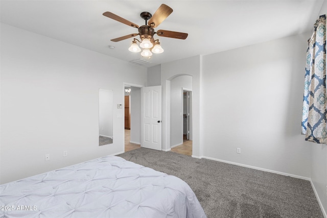 bedroom with baseboards, carpet floors, arched walkways, and ceiling fan