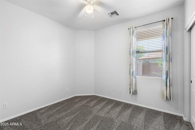 empty room featuring baseboards, visible vents, dark carpet, and ceiling fan