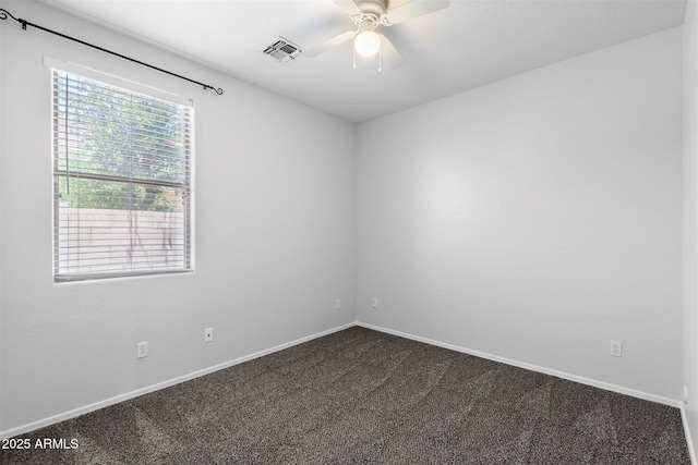 empty room featuring a ceiling fan, visible vents, dark carpet, and baseboards