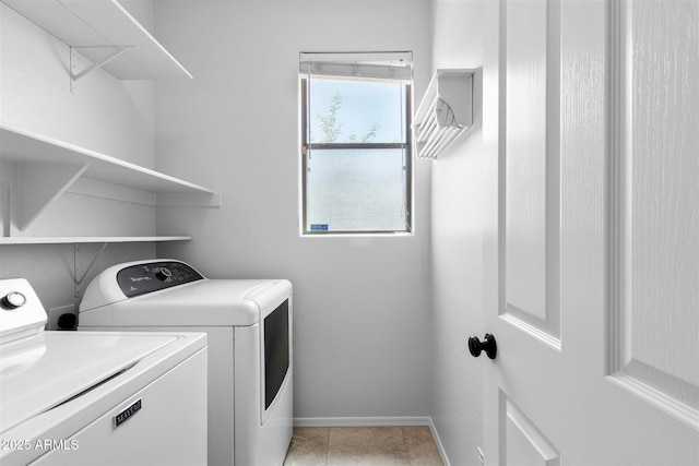 washroom with light tile patterned floors, baseboards, washing machine and dryer, and laundry area