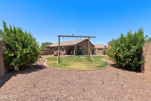 rear view of property featuring a fenced backyard and a lawn