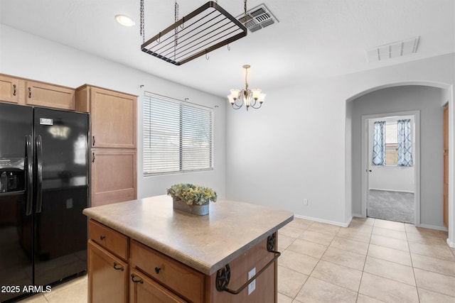 kitchen featuring arched walkways, visible vents, black fridge, and a chandelier