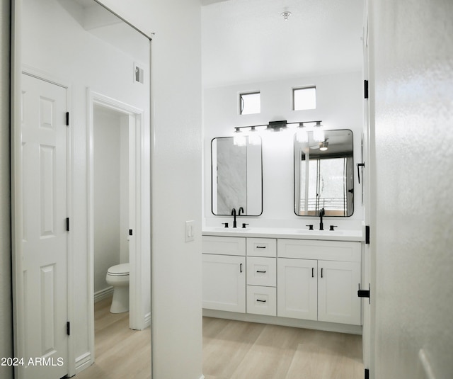 bathroom with toilet, vanity, and wood-type flooring