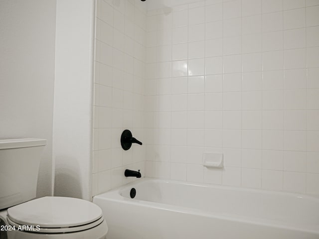 bathroom with toilet and tiled shower / bath combo