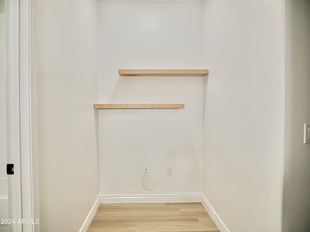 clothes washing area with light hardwood / wood-style flooring