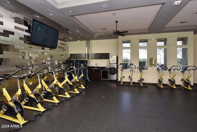 workout area with a raised ceiling and ceiling fan