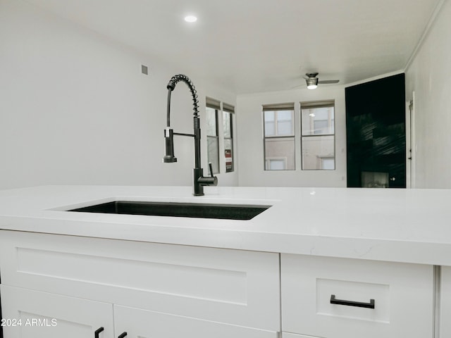 room details with ceiling fan, sink, and white cabinets