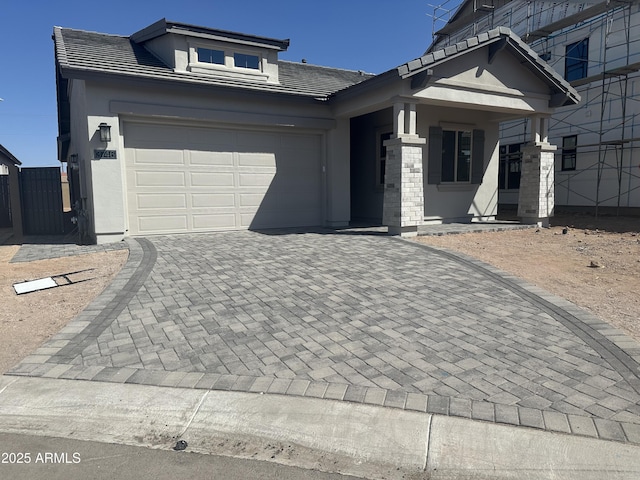 view of front of home featuring stucco siding, a tiled roof, decorative driveway, and a garage