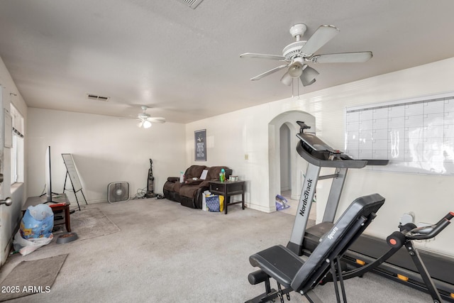 workout room with a ceiling fan, visible vents, arched walkways, and carpet floors