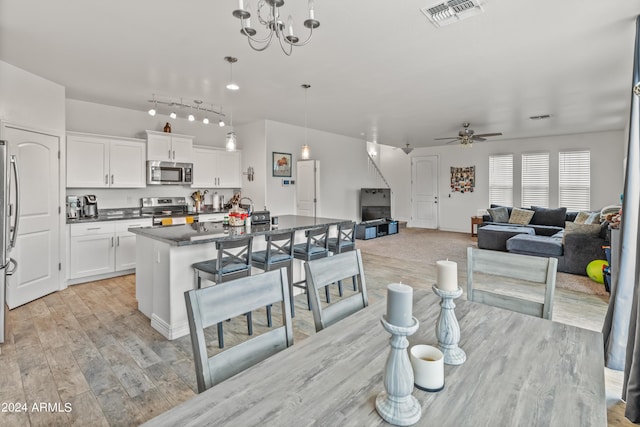 dining area featuring ceiling fan with notable chandelier and light hardwood / wood-style flooring