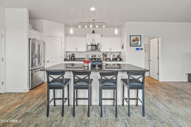 kitchen featuring an island with sink, appliances with stainless steel finishes, a breakfast bar area, and white cabinets