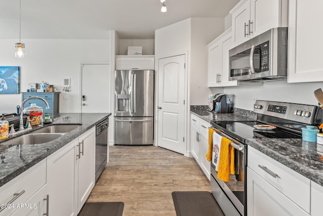 kitchen with pendant lighting, sink, white cabinets, stainless steel appliances, and light wood-type flooring