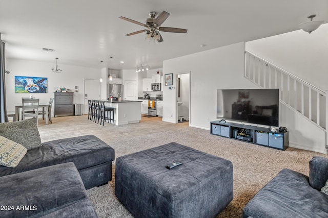 living room with ceiling fan with notable chandelier and light carpet