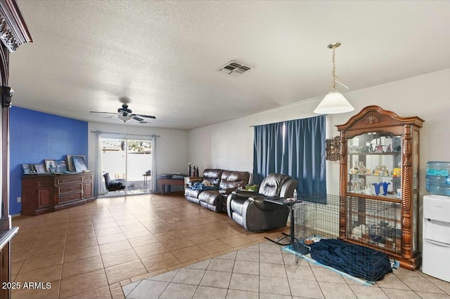 living room featuring a textured ceiling, ceiling fan, visible vents, and tile patterned floors