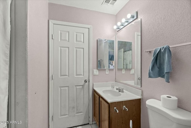 bathroom with toilet, visible vents, and vanity
