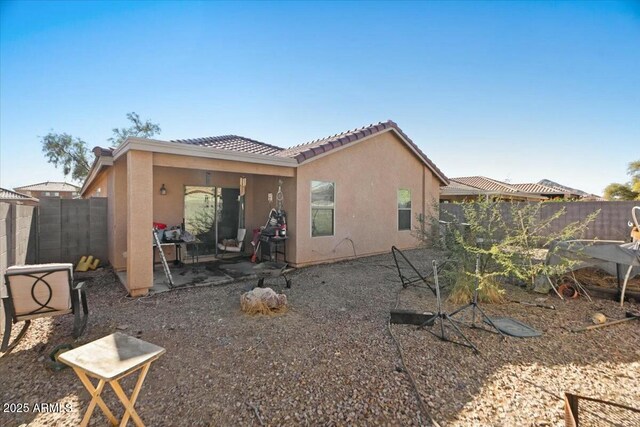 back of property with a fenced backyard, stucco siding, a patio area, and a tile roof