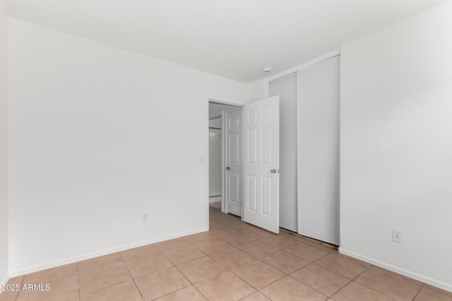 unfurnished bedroom with light tile patterned floors, baseboards, and a closet