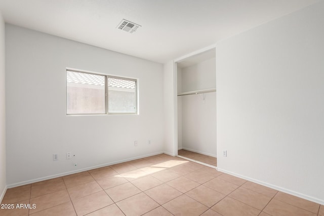 unfurnished bedroom featuring light tile patterned floors, baseboards, a closet, and visible vents