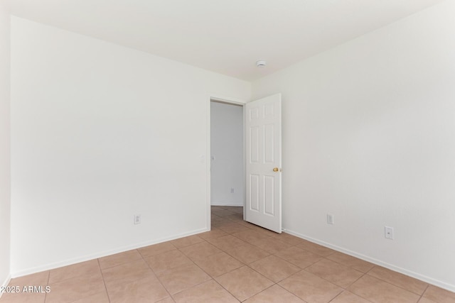 unfurnished room featuring light tile patterned floors and baseboards