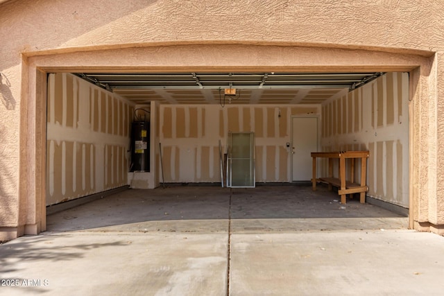 garage with a garage door opener, water heater, and concrete driveway