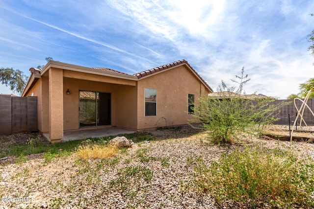 rear view of house featuring a patio, a fenced backyard, stucco siding, and a tile roof