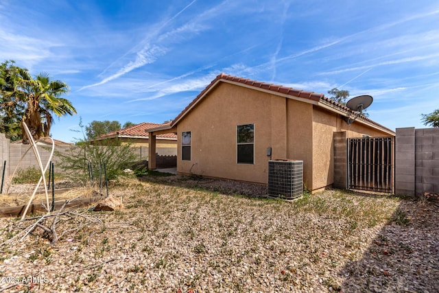 view of home's exterior featuring stucco siding, a gate, central AC, and fence