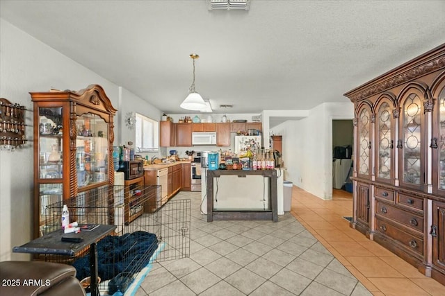 kitchen featuring visible vents, appliances with stainless steel finishes, hanging light fixtures, a sink, and light tile patterned flooring