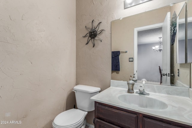 bathroom featuring a textured wall, vanity, toilet, and a textured ceiling