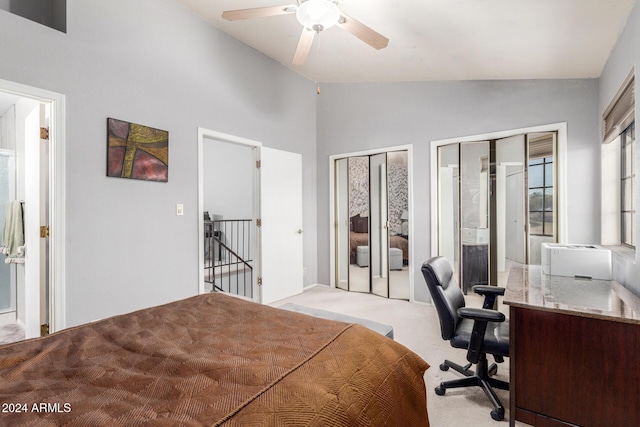 bedroom featuring connected bathroom, light carpet, a ceiling fan, vaulted ceiling, and two closets