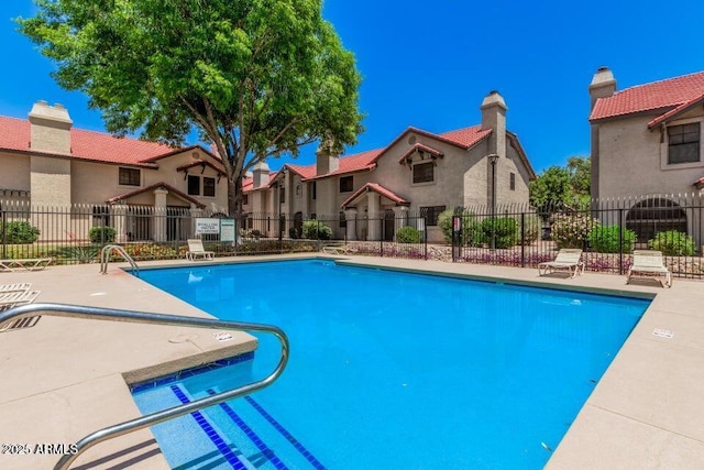 community pool featuring fence and a residential view