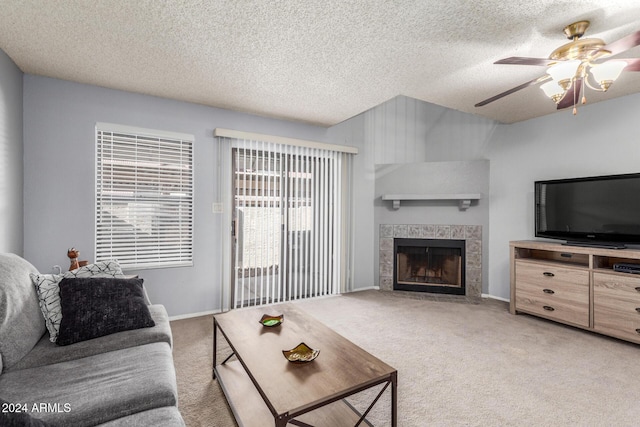 living area with light carpet, ceiling fan, a fireplace, and a textured ceiling