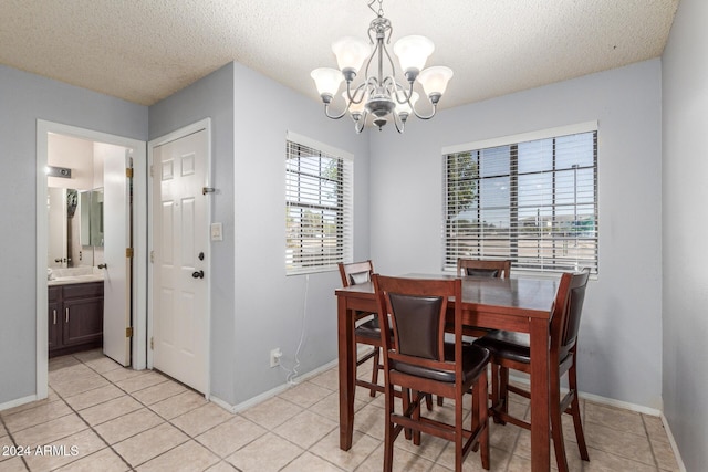 dining room with a textured ceiling, light tile patterned flooring, a notable chandelier, and baseboards