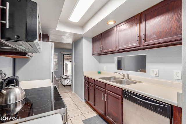 kitchen with a tray ceiling, stainless steel appliances, light countertops, light tile patterned flooring, and a sink