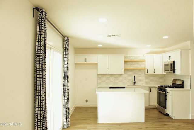 kitchen with white cabinets, light wood-type flooring, stainless steel appliances, and sink