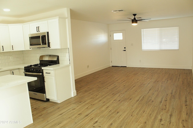 kitchen featuring light wood-type flooring, white cabinetry, appliances with stainless steel finishes, and tasteful backsplash