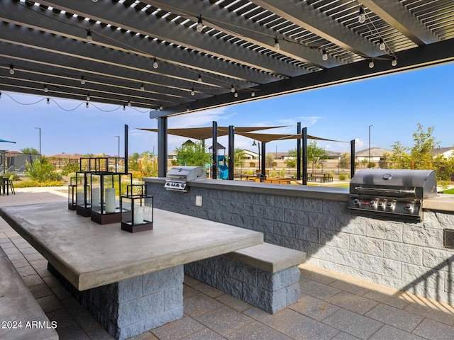 view of patio / terrace featuring a pergola, exterior kitchen, and a grill